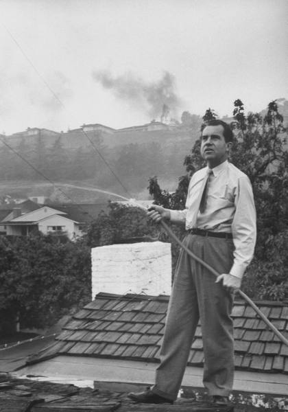 Senator Richard M. Nixon on roof of his home in Los Angeles, putting out fires caused by brush blaze.